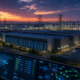 AI data center campus at dusk connected to power transmission lines and operations dashboards